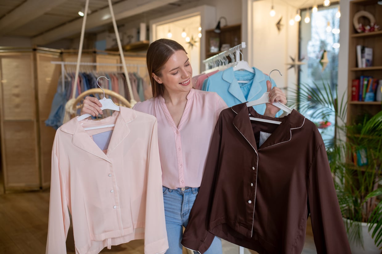 Successful young designer girl demonstrating womens blouses.